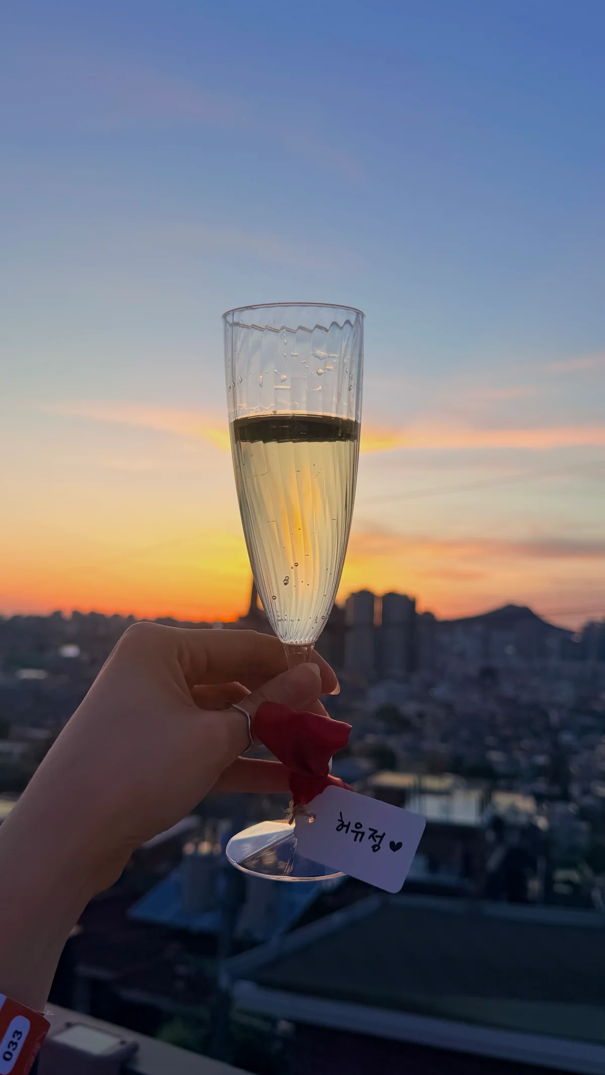 노을을 배경으로 든 샴페인 글라스와 이름표