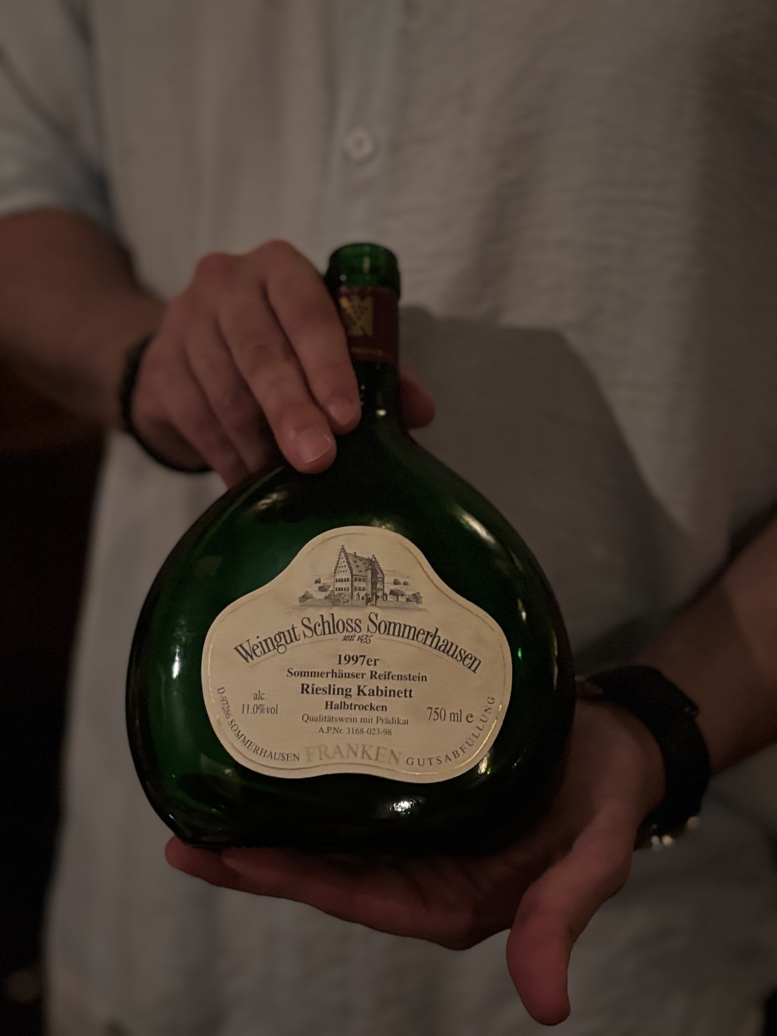 손에 들린 1997 Schloss Sommerhausen Riesling Kabinett Halbtrocken 병